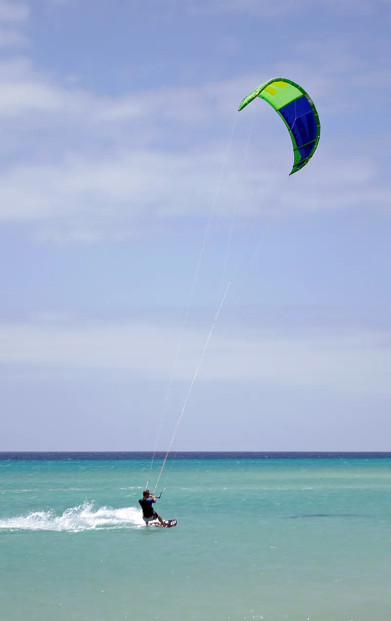 Kitesurfista navegando sobre agua turquesa poco profunda